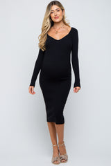 woman wearing a black long sleeve maternity dress, showcasing her baby bump
