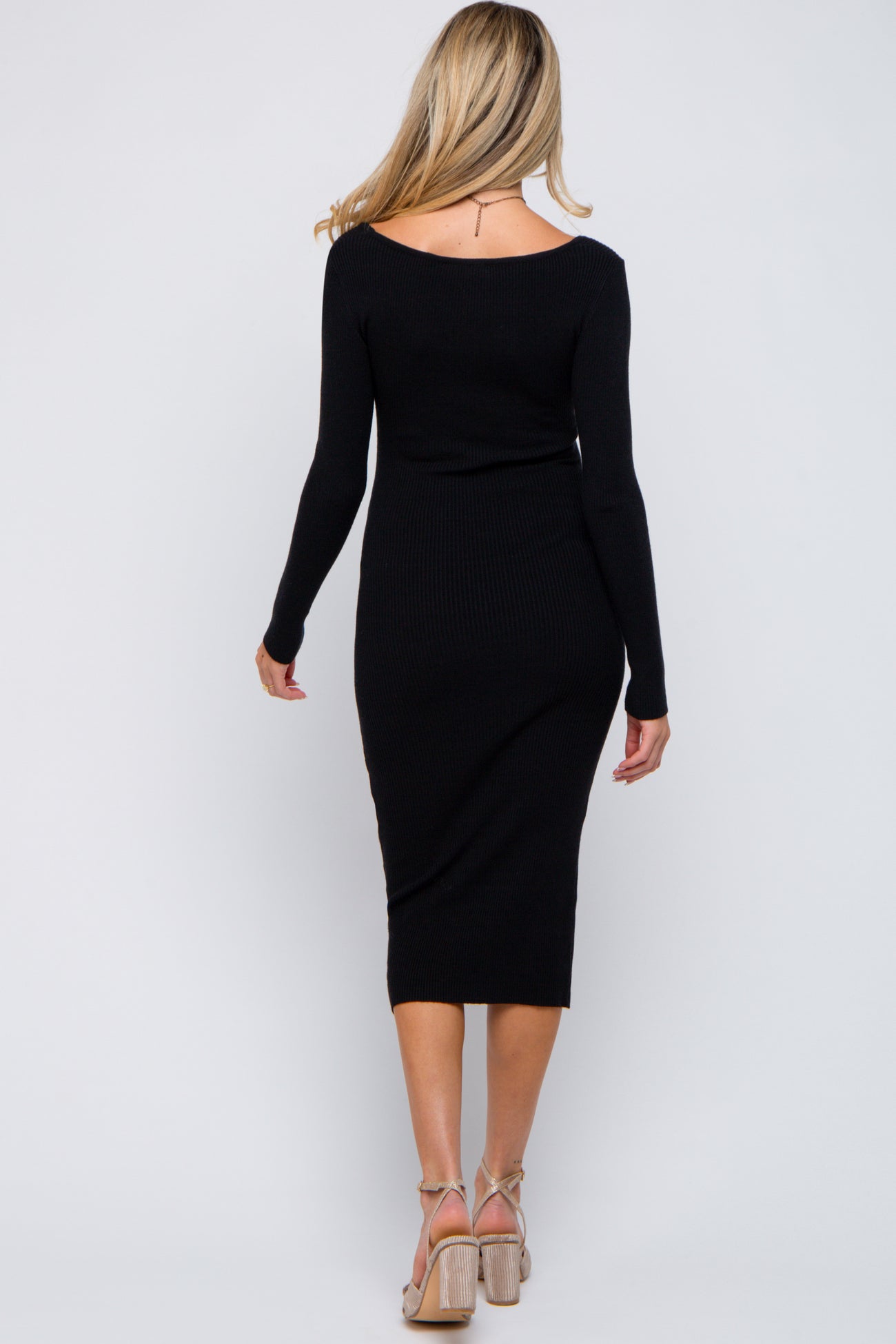 woman wearing a fitted black ribbed maternity dress with long sleeves and a midi length