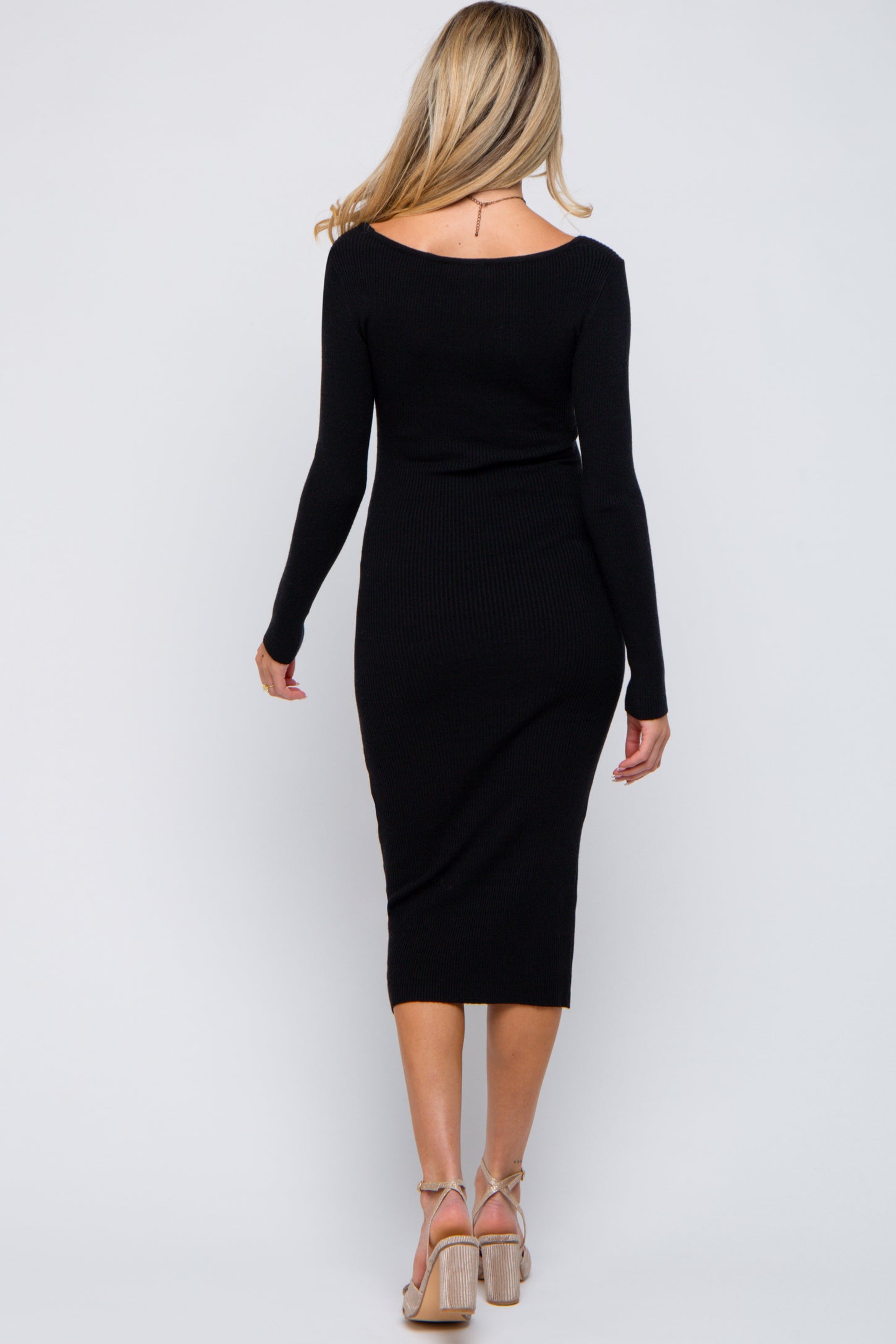 woman wearing a fitted black ribbed maternity dress with long sleeves and a midi length