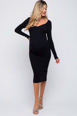 woman wearing a black ribbed maternity dress with a v-neck and long sleeves, showcasing her baby bump