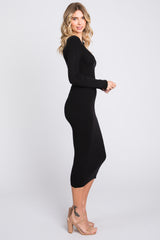 woman wearing a black ribbed long sleeve midi dress and nude strappy heels in a side profile stance