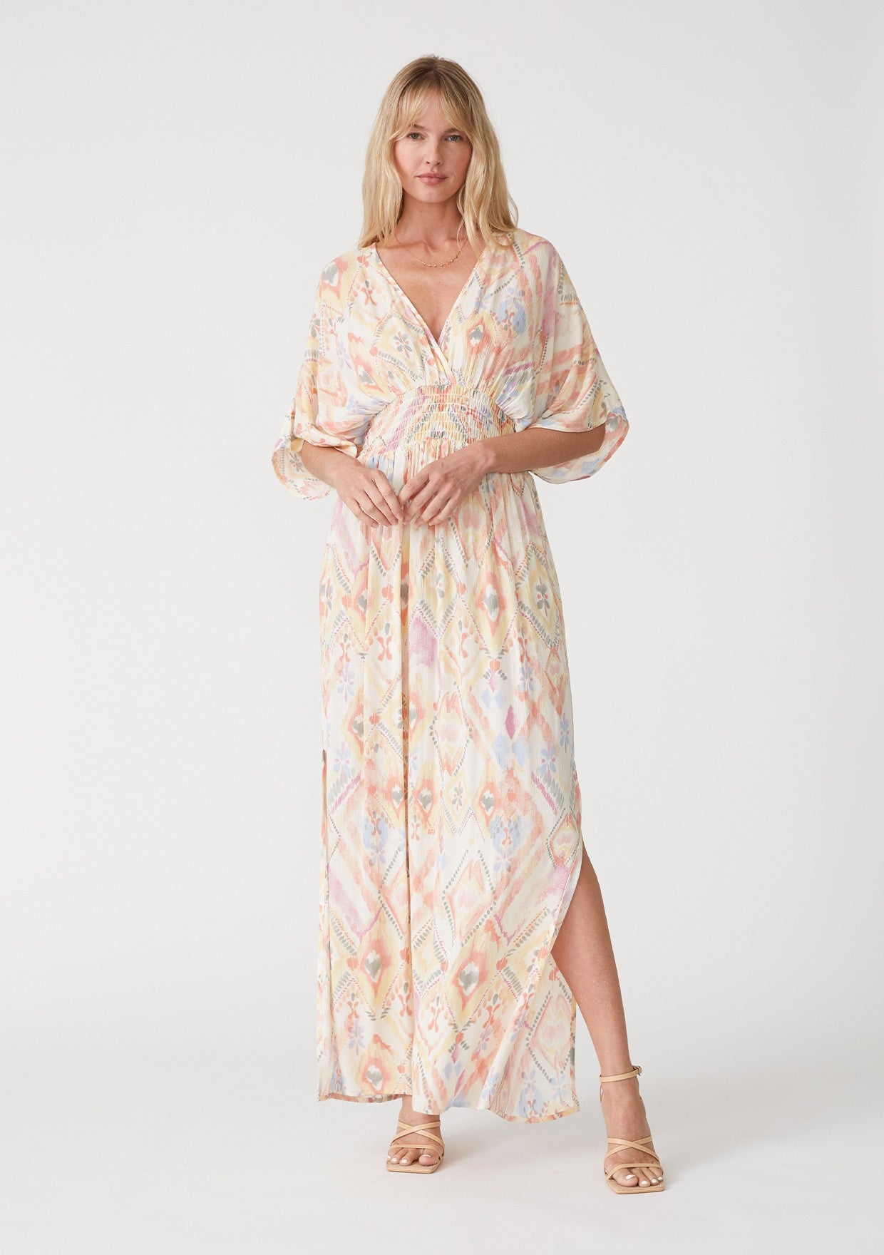 woman wearing a colorful patterned maxi dress with a v-neckline and slits on the sides