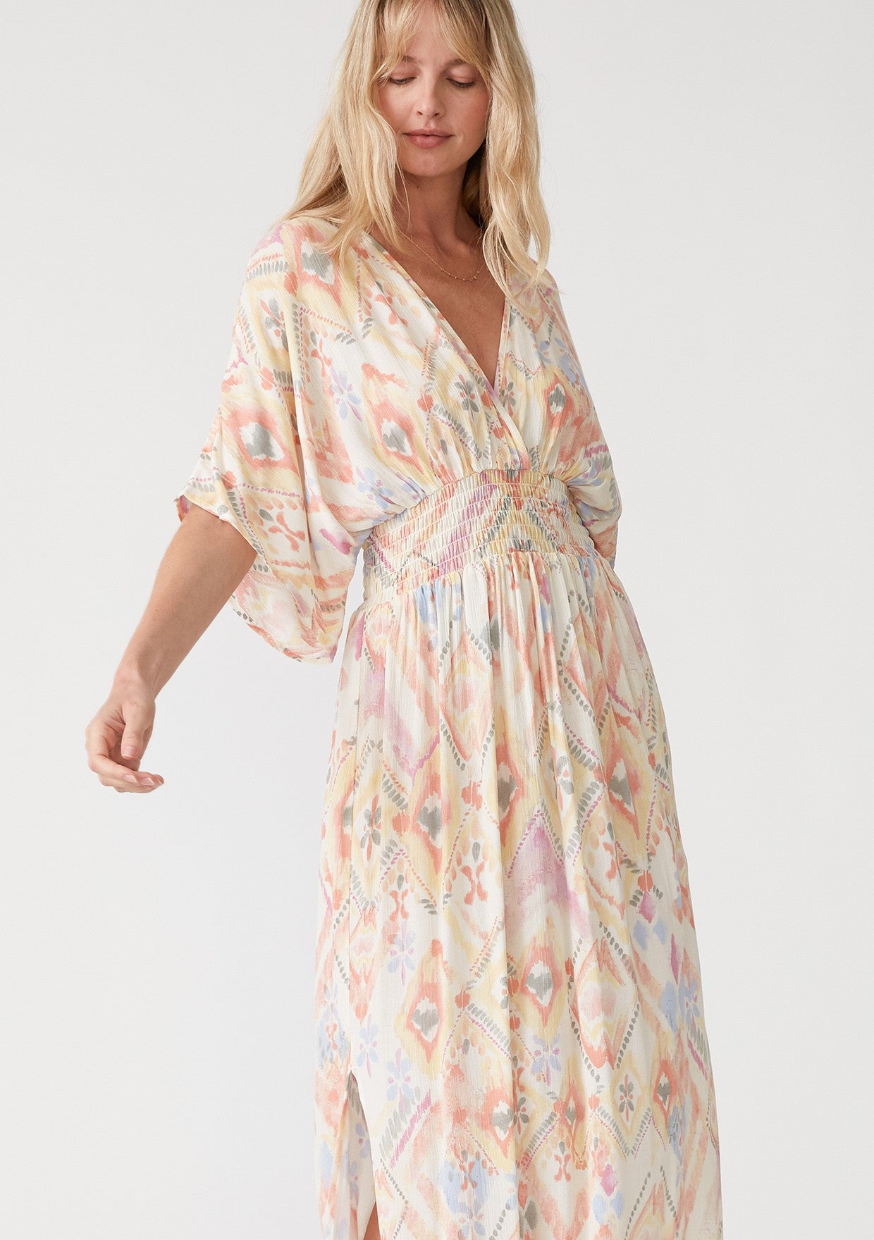 woman wearing a colorful patterned maxi dress with a smocked waist and wide sleeves