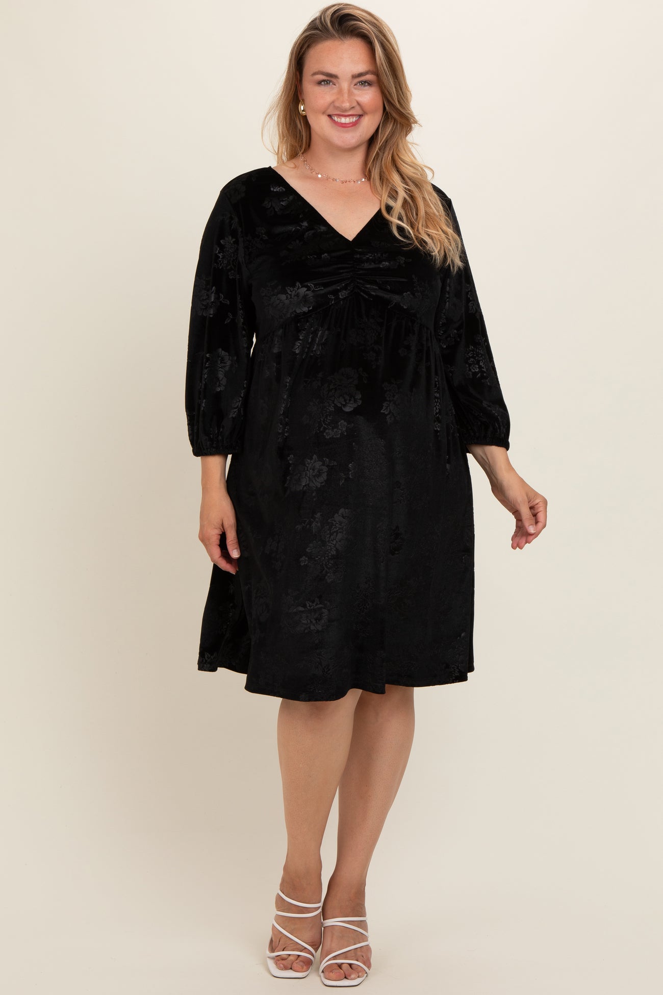 woman wearing a black velvet maternity plus dress with v-neckline and 3/4 sleeves, visible baby bump