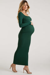 woman wearing a green long sleeve form-fitting maternity dress and cradling her baby bump