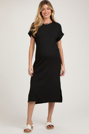 woman wearing a black short sleeve maternity dress with side slits and a relaxed fit, highlighting her baby bump