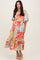 woman wearing a colorful floral maxi dress with puff sleeves and a smocked bodice, standing against a neutral background