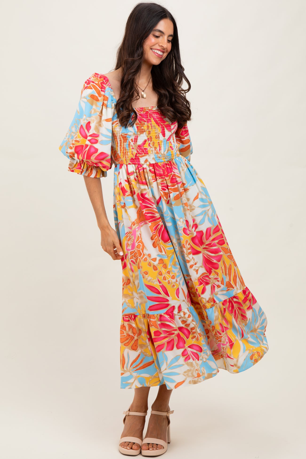 woman wearing a colorful floral maxi dress with puff sleeves and a smocked bodice
