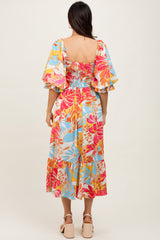 woman wearing a colorful floral smocked maxi dress with puff sleeves, shown from the back