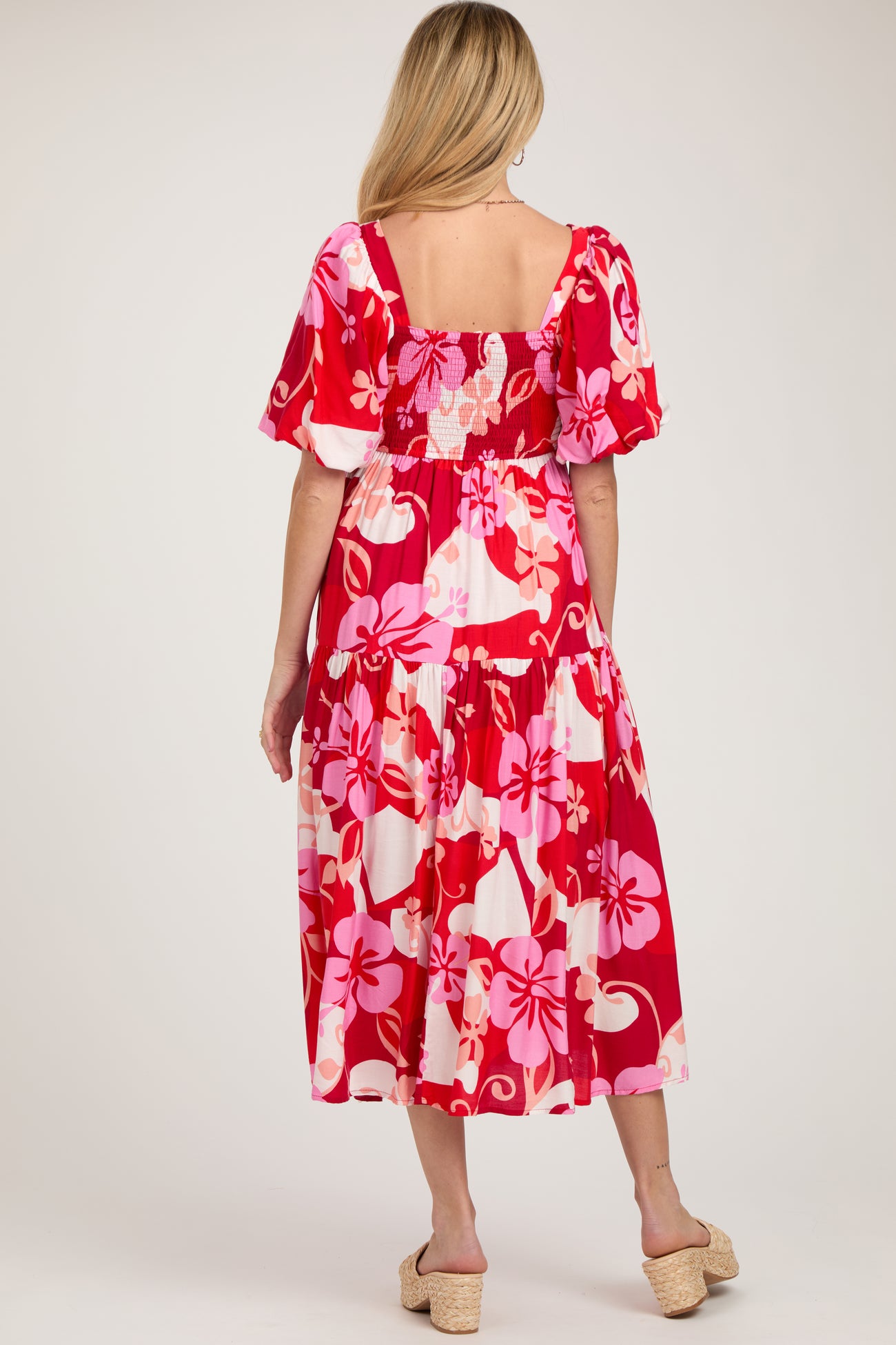 woman wearing a red floral maternity dress with puff sleeves and a smocked back, showing a baby bump