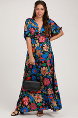 woman wearing a vibrant floral print maternity maxi dress with short sleeves and holding a black handbag, baby bump visible