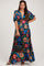 woman wearing a vibrant floral print maternity maxi dress with short sleeves and holding a black handbag, baby bump visible