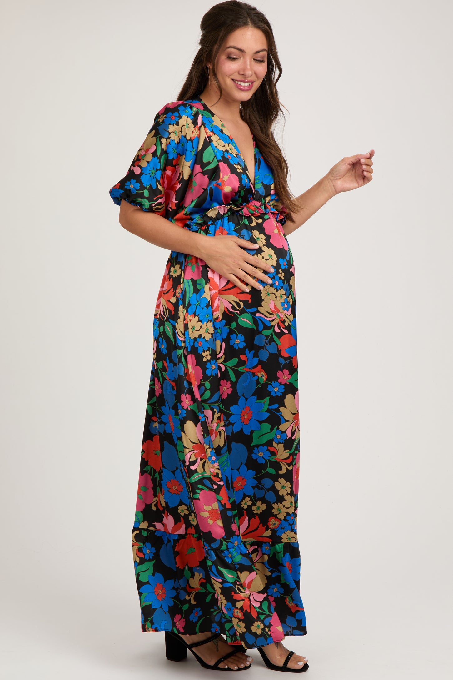 woman wearing a black floral maternity maxi dress and holding her baby bump