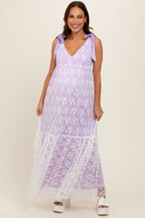 woman wearing a lavender maternity maxi dress with floral details and lace accents, holding the dress while smiling