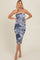 woman wearing a blue and white tie-dye midi dress with ruching and a side slit, standing with hands on hips