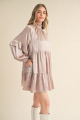 woman wearing a blush pink long sleeve tiered mini dress with ruffled details and side pockets