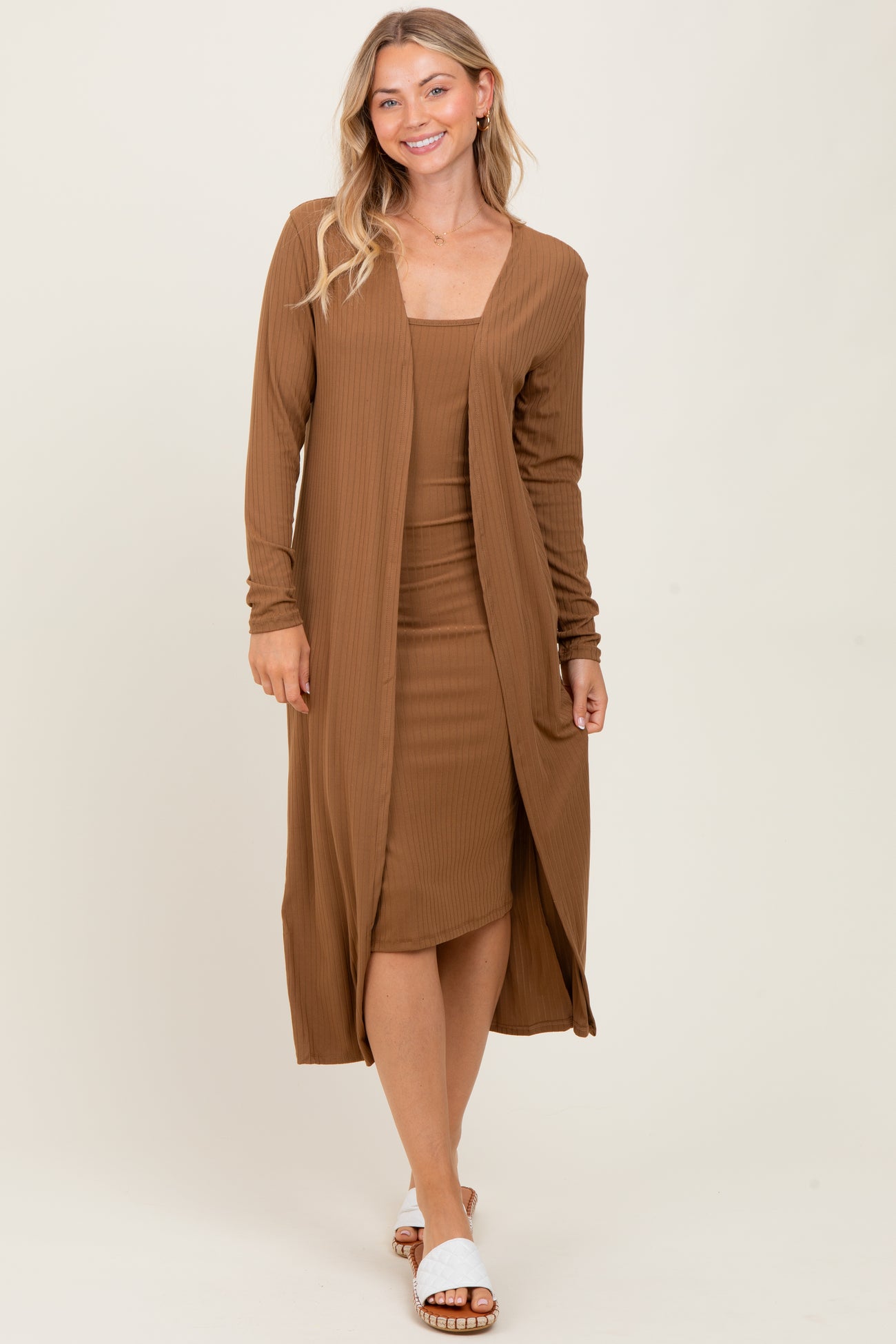 woman wearing a brown ribbed midi dress with a matching long cardigan and white slide sandals