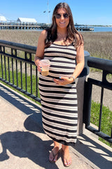 woman wearing a black and white striped maternity maxi dress while holding a drink by the waterfront