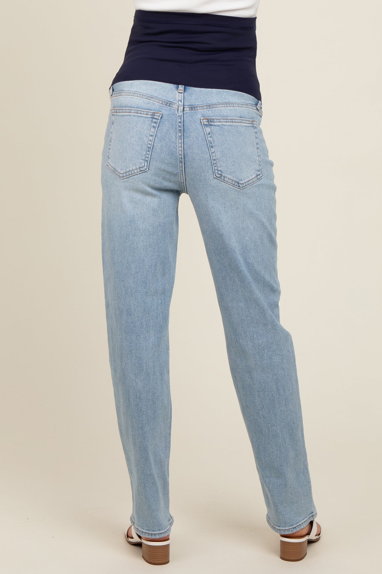 maternity wear in light blue straight leg jeans with a dark blue supportive waistband, model viewed from the back