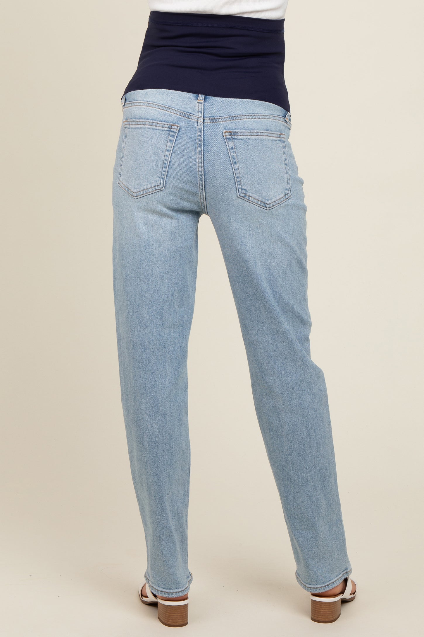 maternity wear in light blue straight leg jeans with a dark blue supportive waistband, model viewed from the back