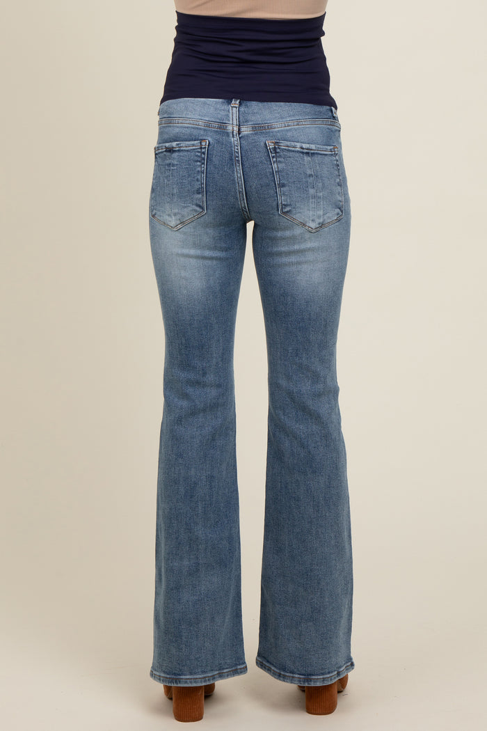 woman wearing light blue maternity flared jeans, viewed from the back, showcasing the fitted waist and pockets