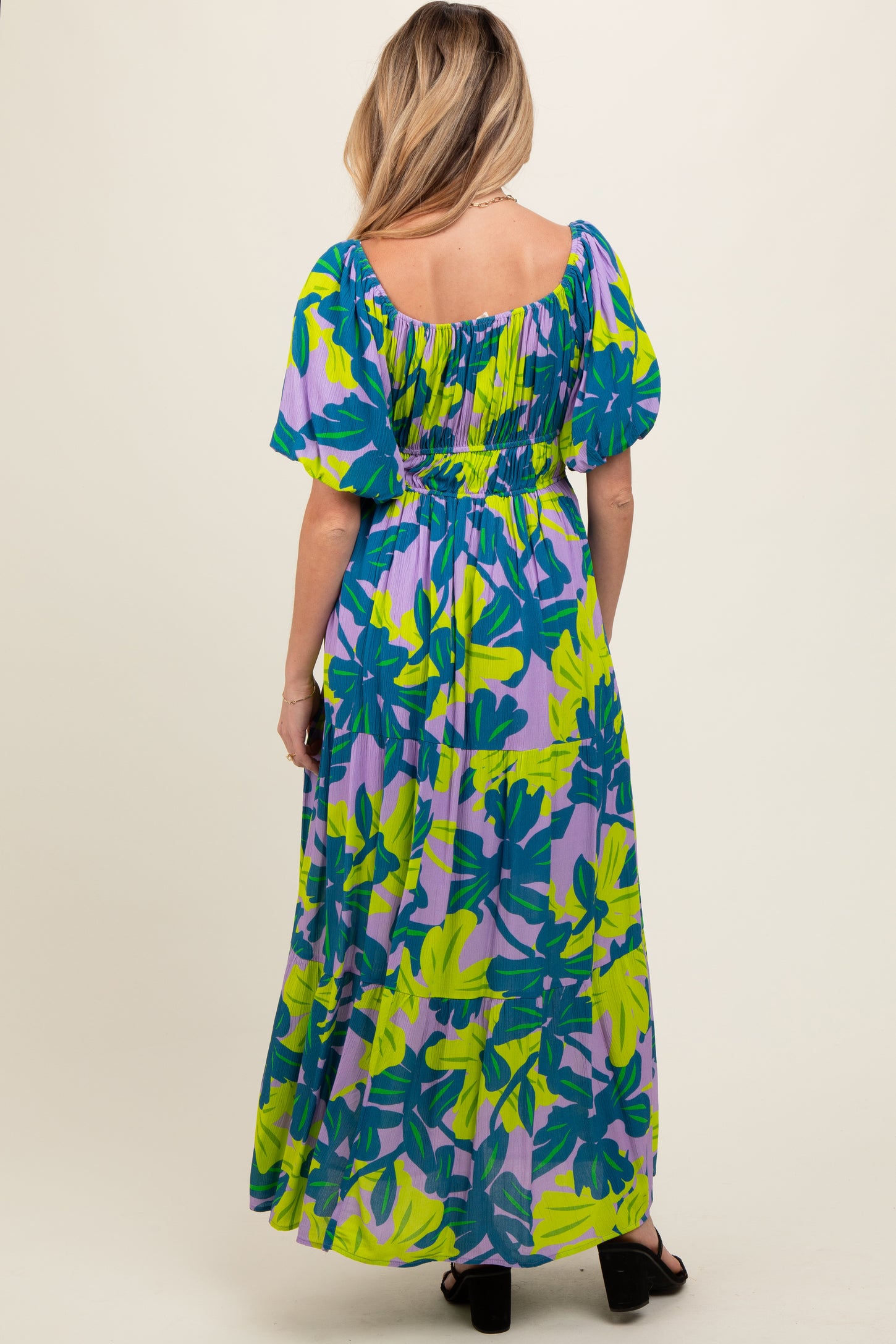 woman wearing a colorful floral print maternity maxi dress with puff sleeves and a smocked waist, showing a baby bump