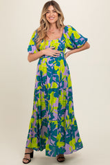 woman wearing a purple and green floral maternity maxi dress and holding her baby bump