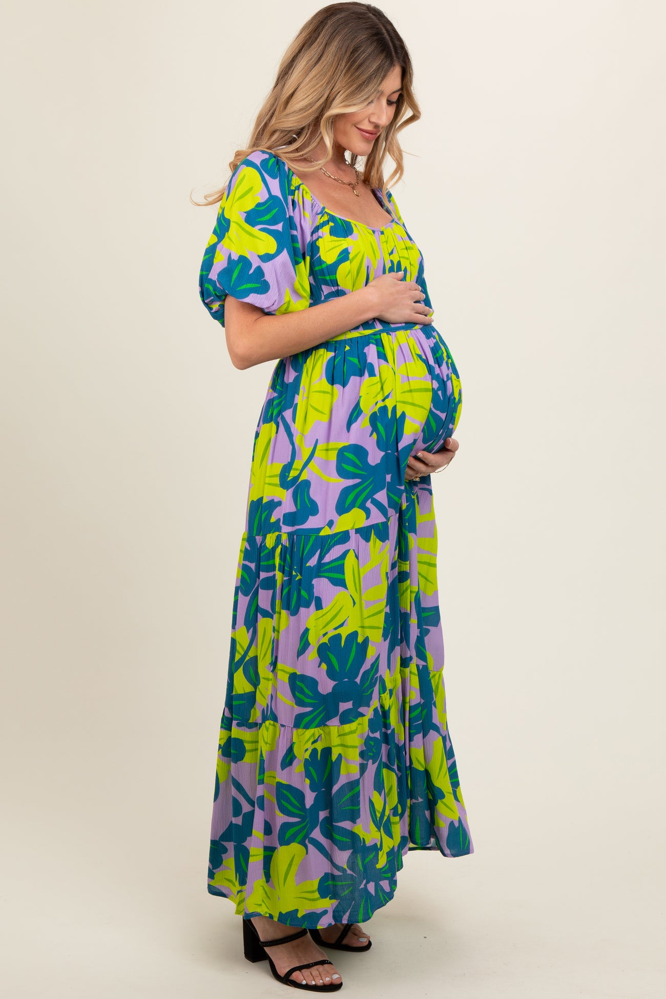 woman wearing a colorful floral maternity maxi dress and showcasing her baby bump