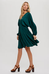 woman wearing a teal short sleeve dress with a cinched waist and flowing skirt, paired with brown block heeled shoes