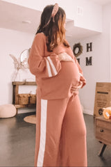 woman wearing a dusty rose maternity loungewear set with stripe details and holding her baby bump