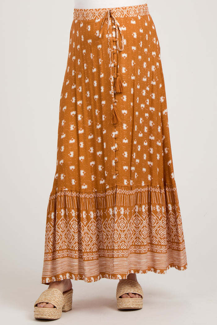 woman wearing a rust colored floral print maternity maxi skirt with a tie waist and tiered hem