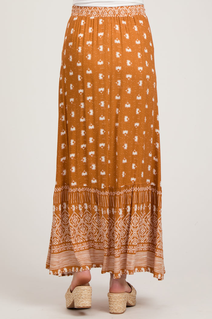 woman wearing a rust-colored maternity skirt with white floral print and tiered design, showing the back view