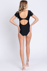 woman wearing a black one-piece swimsuit with ruffle sleeves and open back detail