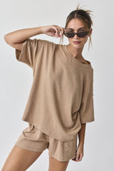 woman wearing a beige oversized short sleeve top and matching shorts, styled with sunglasses