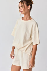 woman wearing a casual cream-colored oversized short sleeve top and matching shorts