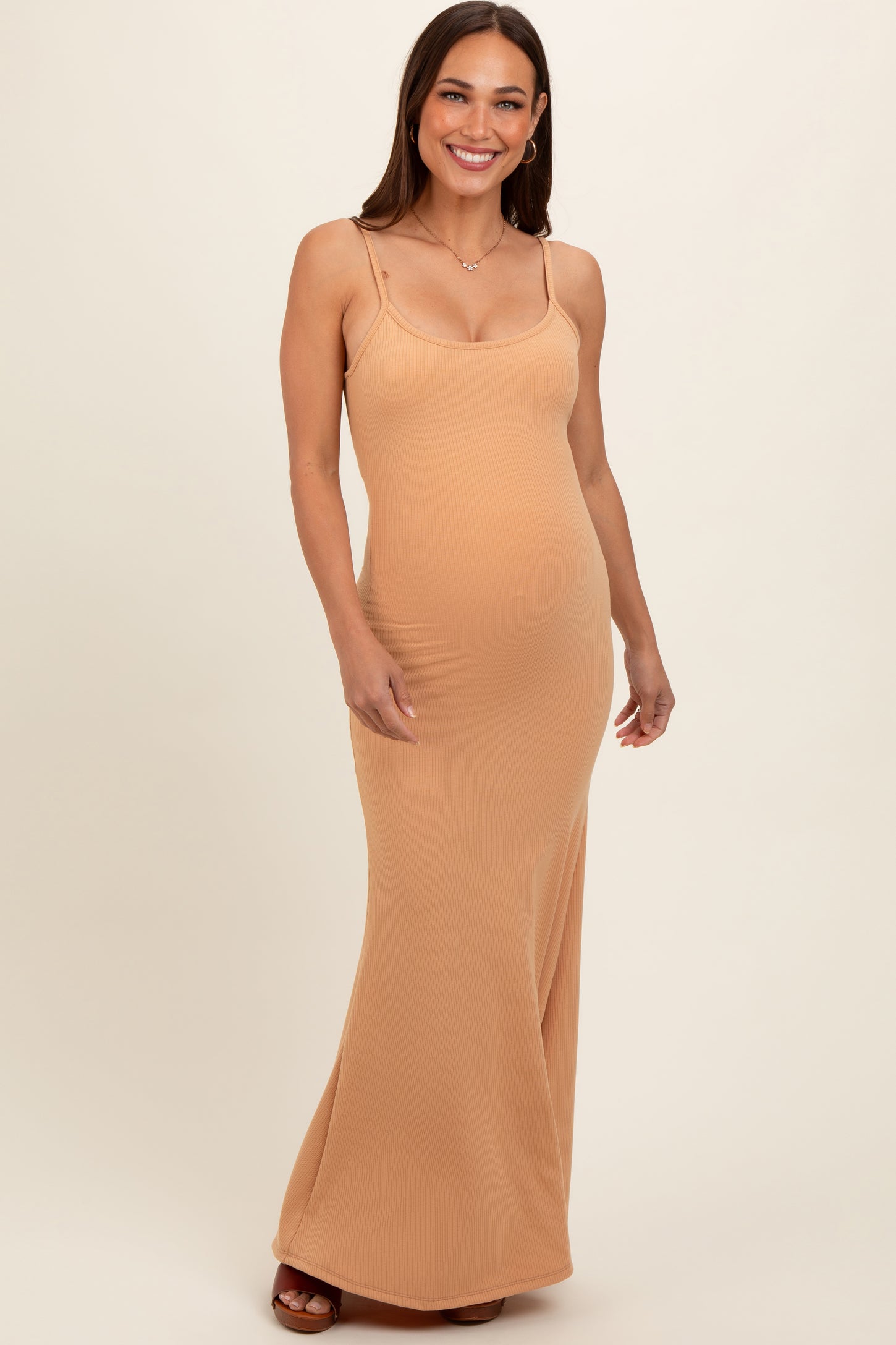 woman wearing a tan ribbed maternity maxi dress with spaghetti straps and a baby bump visible