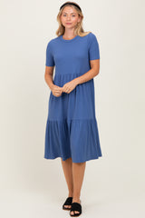 woman wearing a blue short sleeve tiered dress with a round neckline and a loose fit