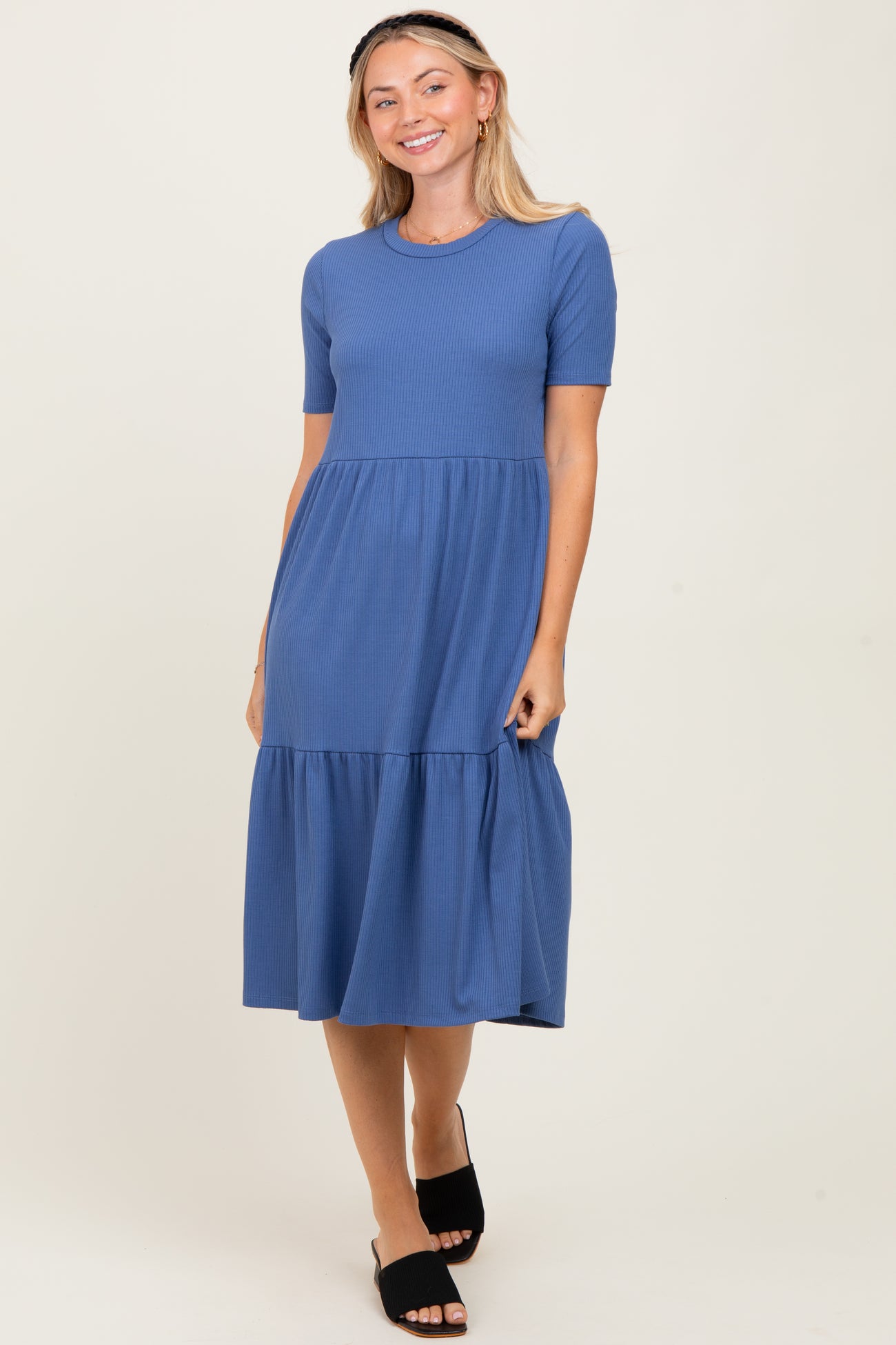 woman wearing a short sleeve blue tiered midi dress and black slide sandals