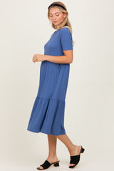 woman wearing a blue short sleeve tiered midi dress and black slide sandals