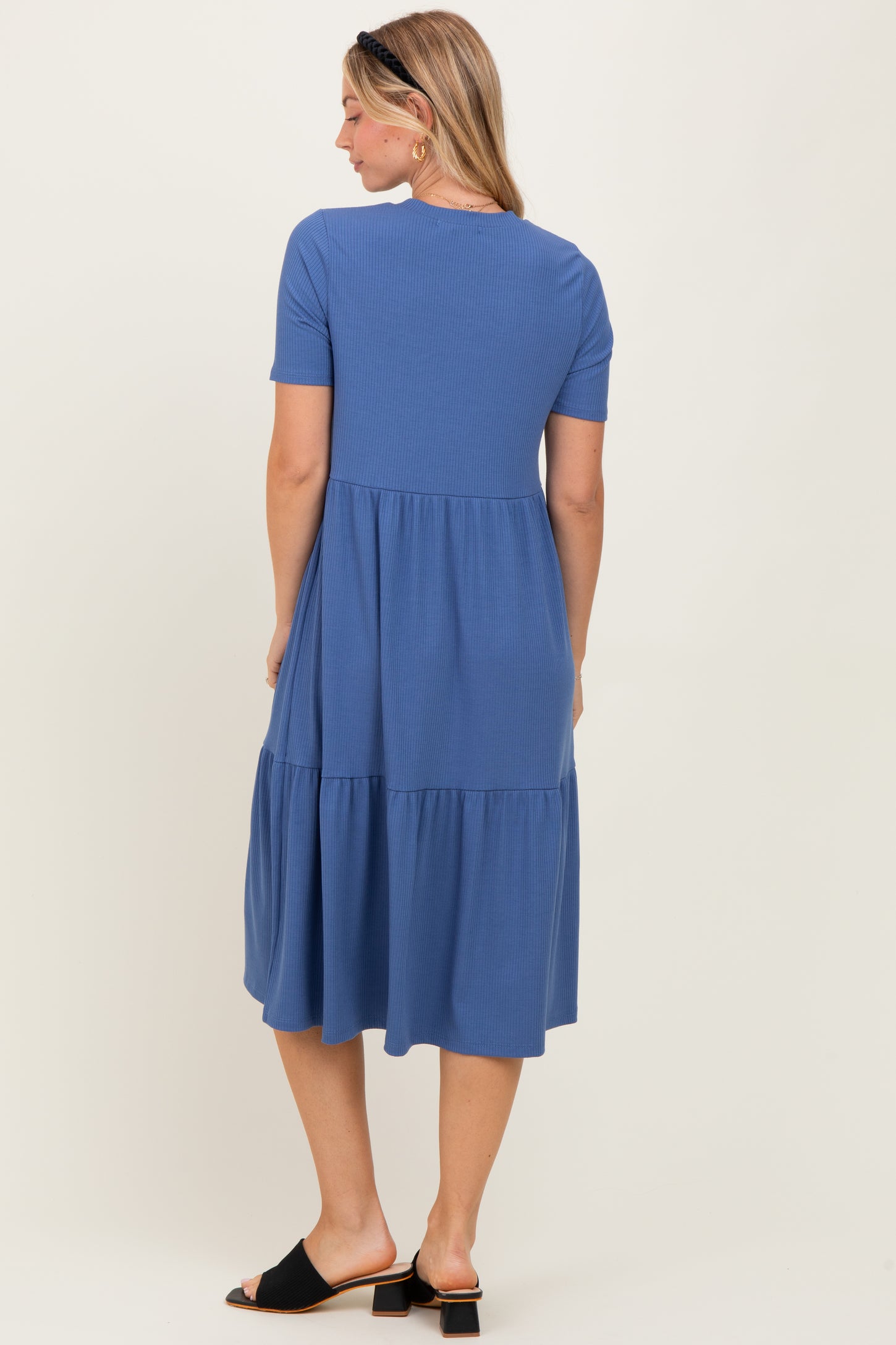 woman wearing a blue short sleeve tiered midi dress, standing with her back to the camera