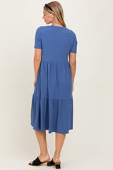woman wearing a blue short sleeve tiered midi dress, standing with her back to the camera