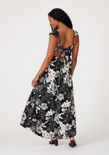 woman wearing a black and white floral maxi dress with a back tie detail and cap sleeves