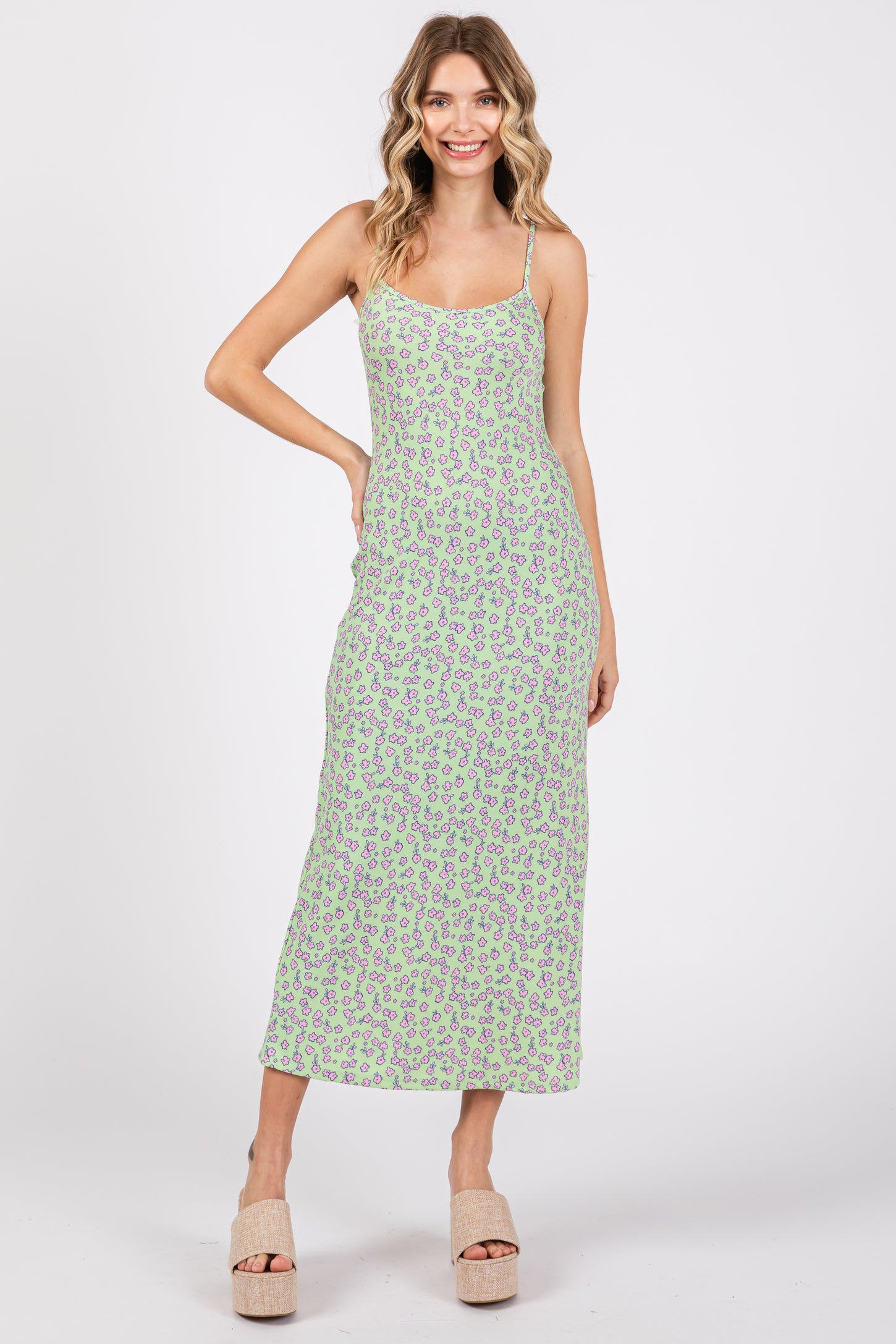 woman wearing a long green floral print maxi dress with thin straps and a fitted silhouette