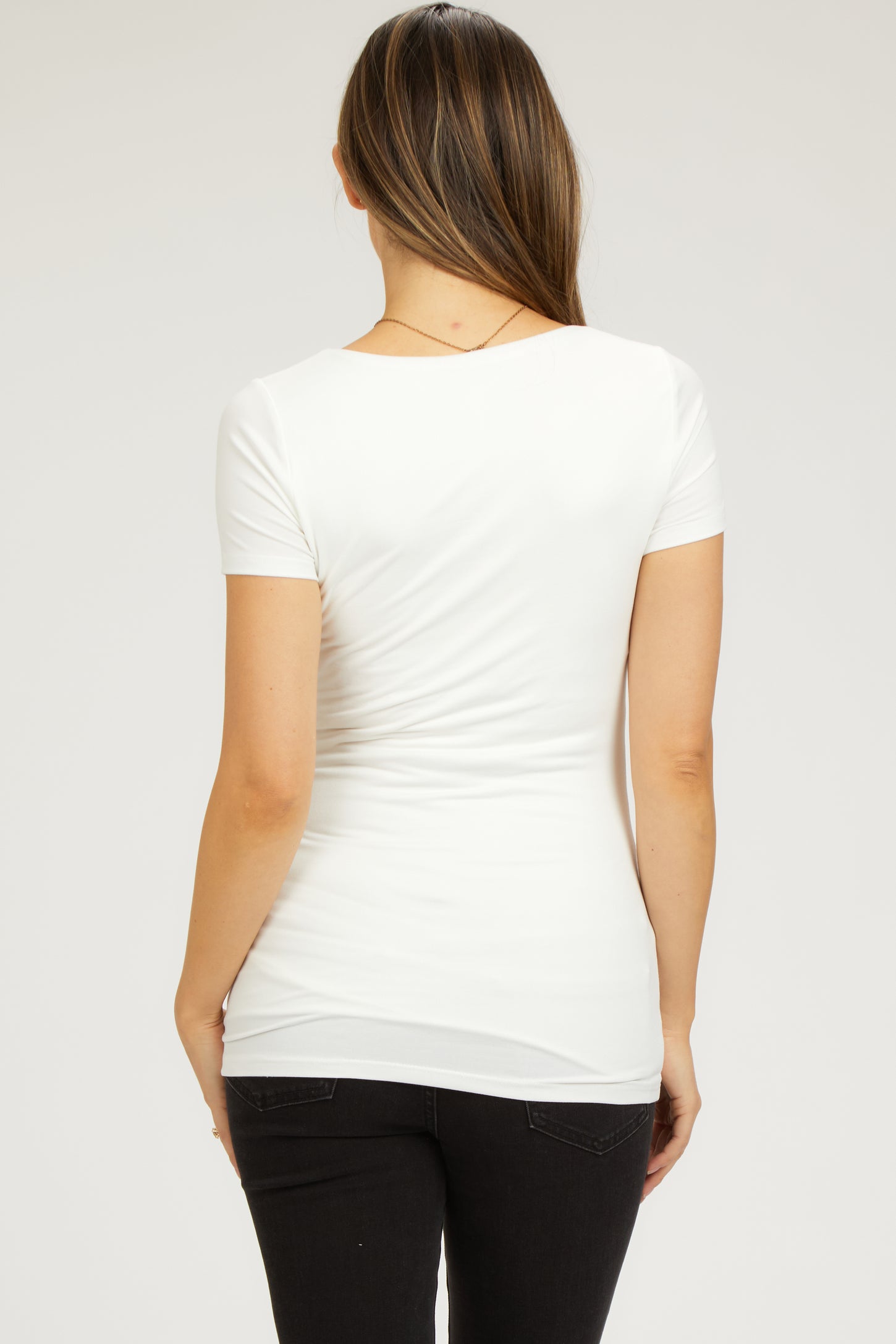 woman wearing a white short sleeve maternity top, shown from the back with a fitted style and smooth fabric