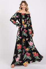 woman wearing a black off-shoulder maxi dress with colorful floral prints and long sleeves