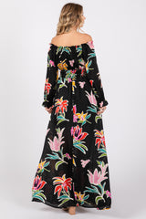 woman wearing a black off-the-shoulder maxi dress with colorful floral prints and long sleeves