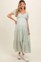 woman wearing a floral print maternity maxi dress with puff sleeves and a tiered hem, showcasing her baby bump