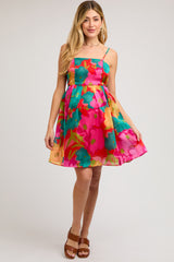 woman wearing a bright floral maternity dress with thin straps and a flared skirt