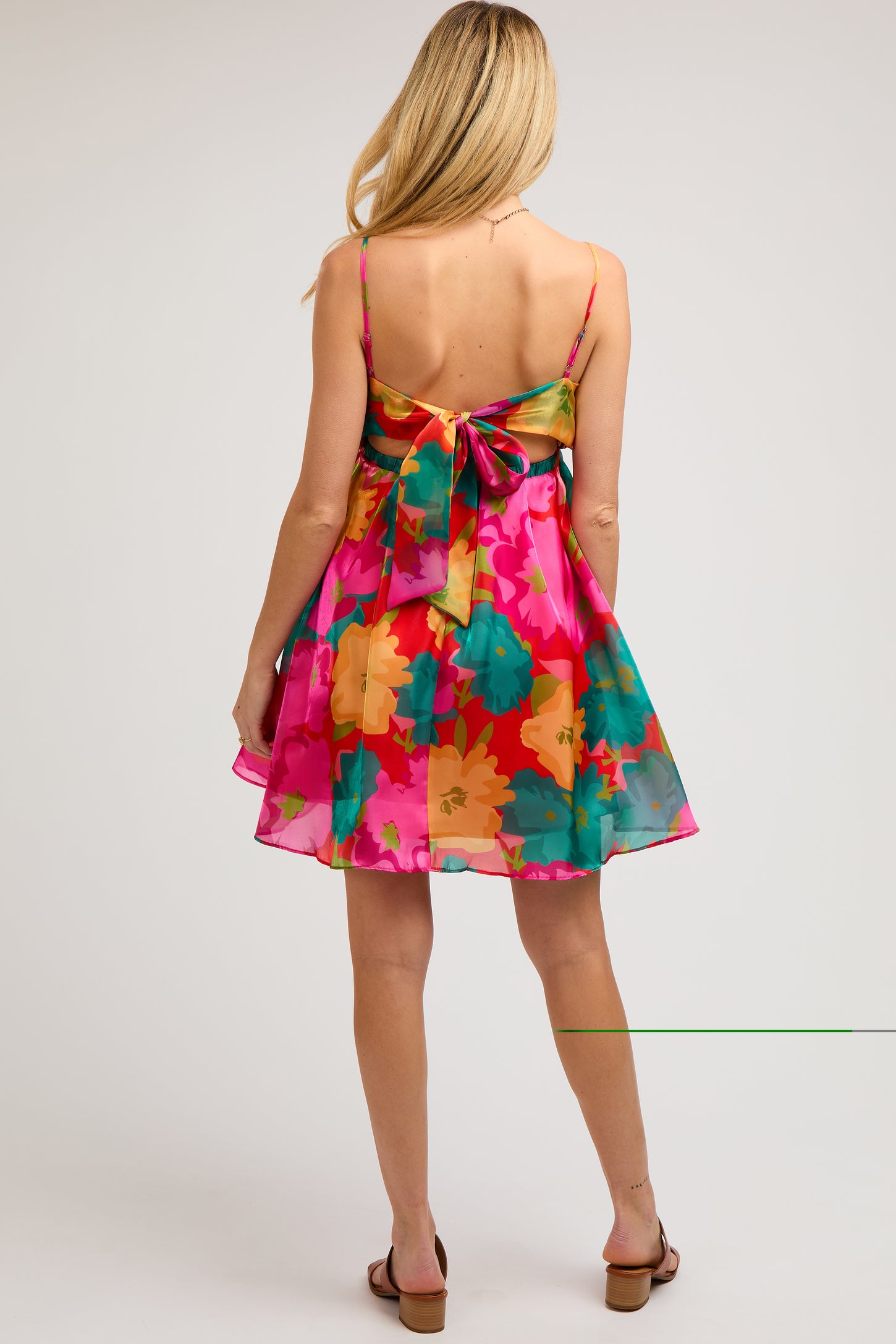 woman wearing a vibrant pink floral maternity dress with a bow detail at the back and a flowing skirt