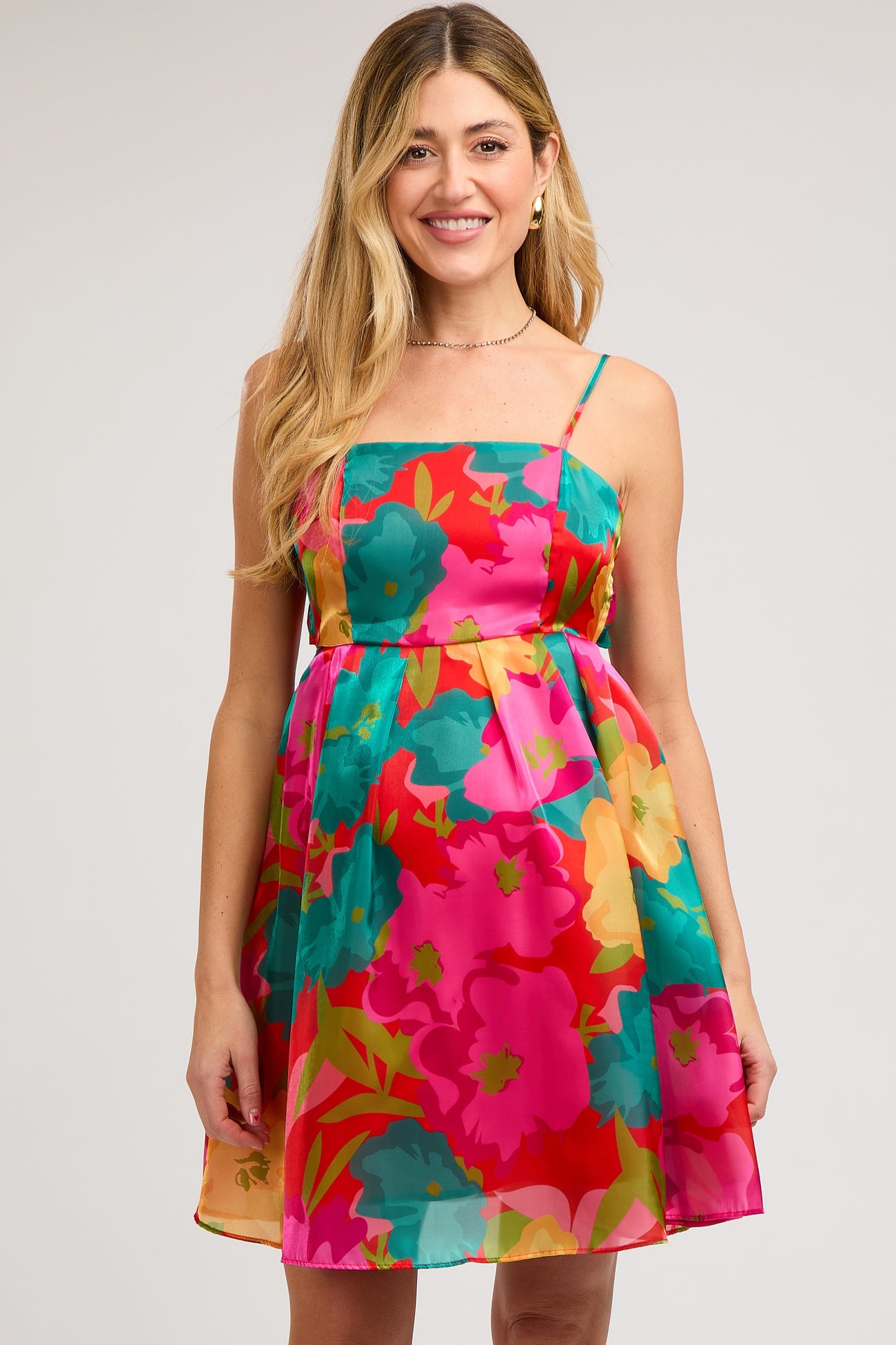woman wearing a colorful floral maternity dress with a fitted bodice and flowy skirt, showing off her baby bump